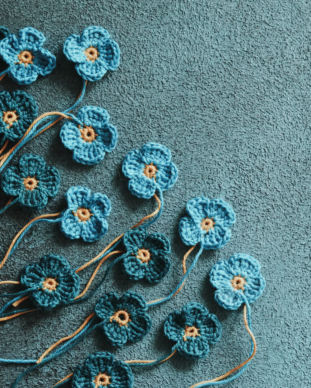 Small blue crocheted flowers on textured fabric