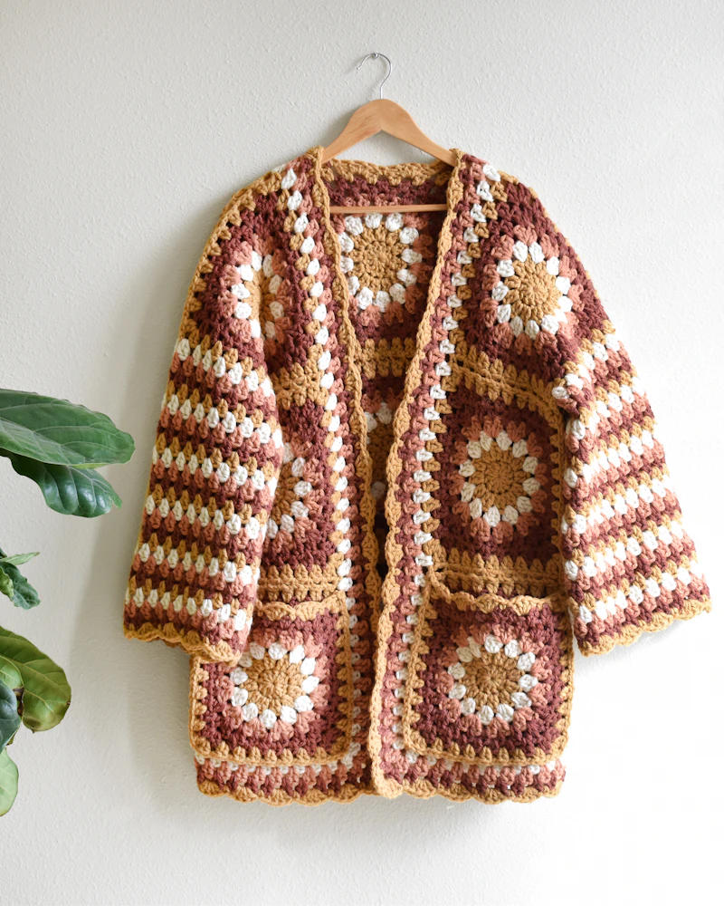 Granny-square crochet cardigan hanging on a wall